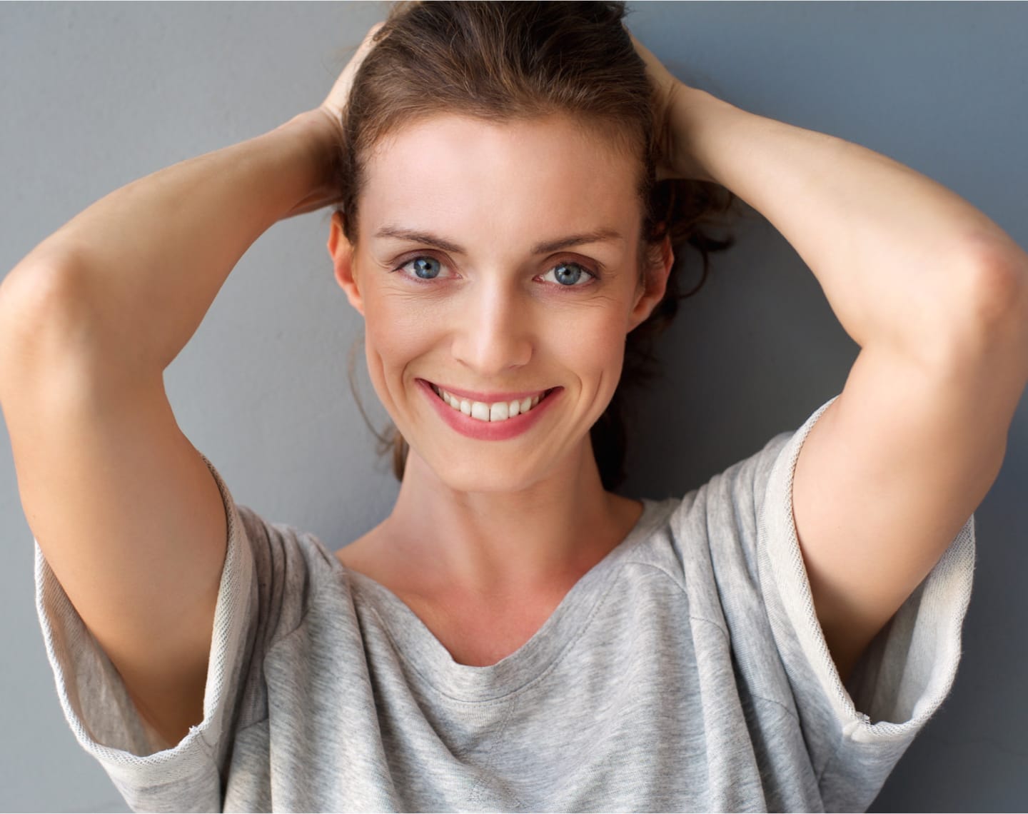 Woman smiling with hands raised up to her head