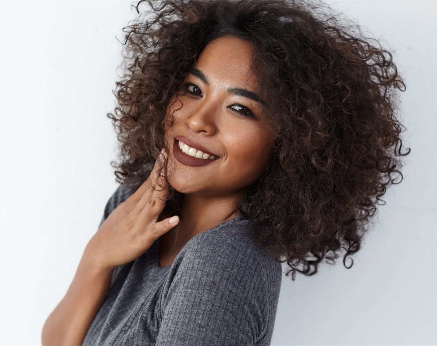 Woman with curly hair, touching her face